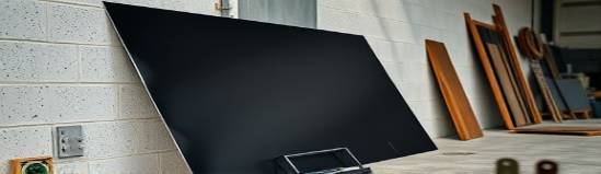 flexible black plastic sheets, matte finish, fanned out, photorealistic, leaning against a workshop wall, highly detailed, subtle air movement, detailed surface, obsidian black, natural skylight, shot with a 35mm lens